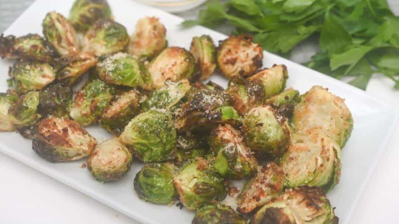 Air-fried brussels sprouts with grated parmesan cheese on a white plate.