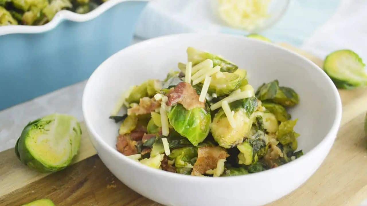 Brussels sprouts and bacon in a bowl on a cutting board.