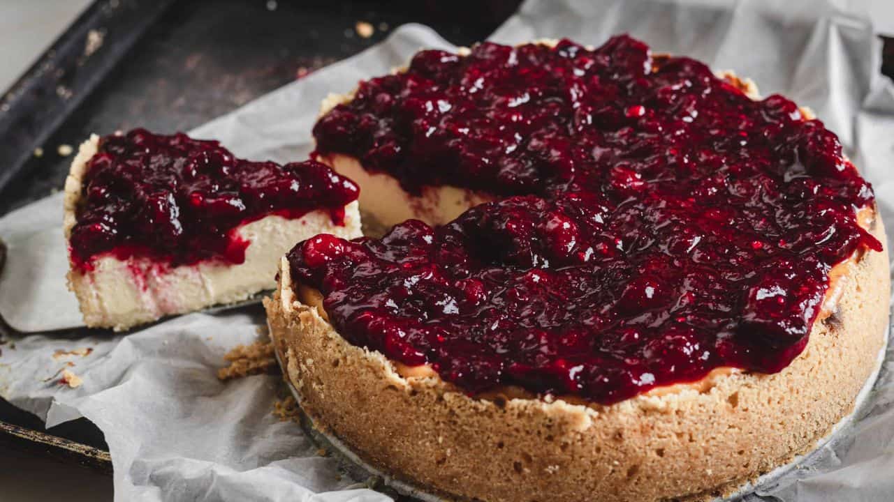 A slice of cheesecake with cranberry sauce on top.