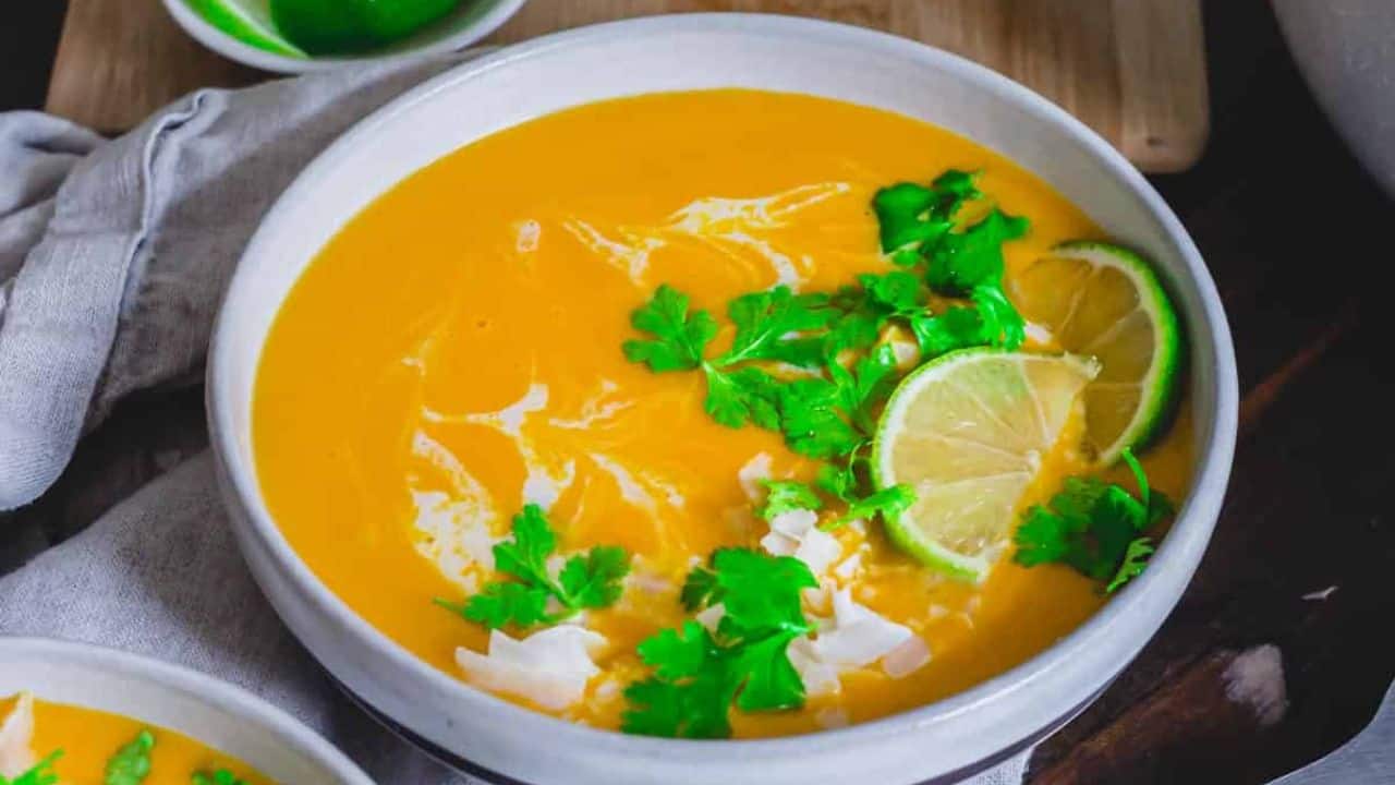 Two bowls of Thai buttercup squash soup with lime and cilantro.