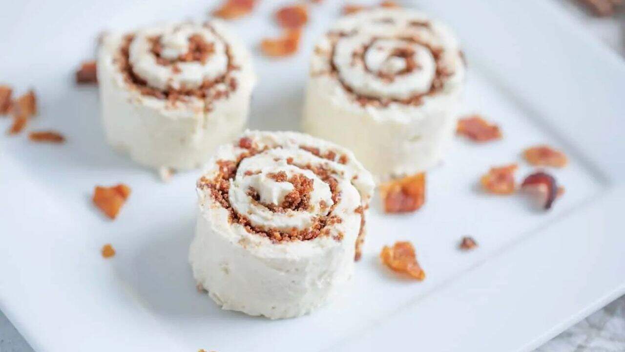 Three cinnamon roll cakes on a white plate.