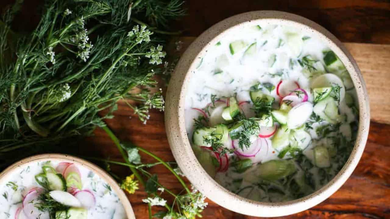 Two bowls of soup with radishes and herbs.