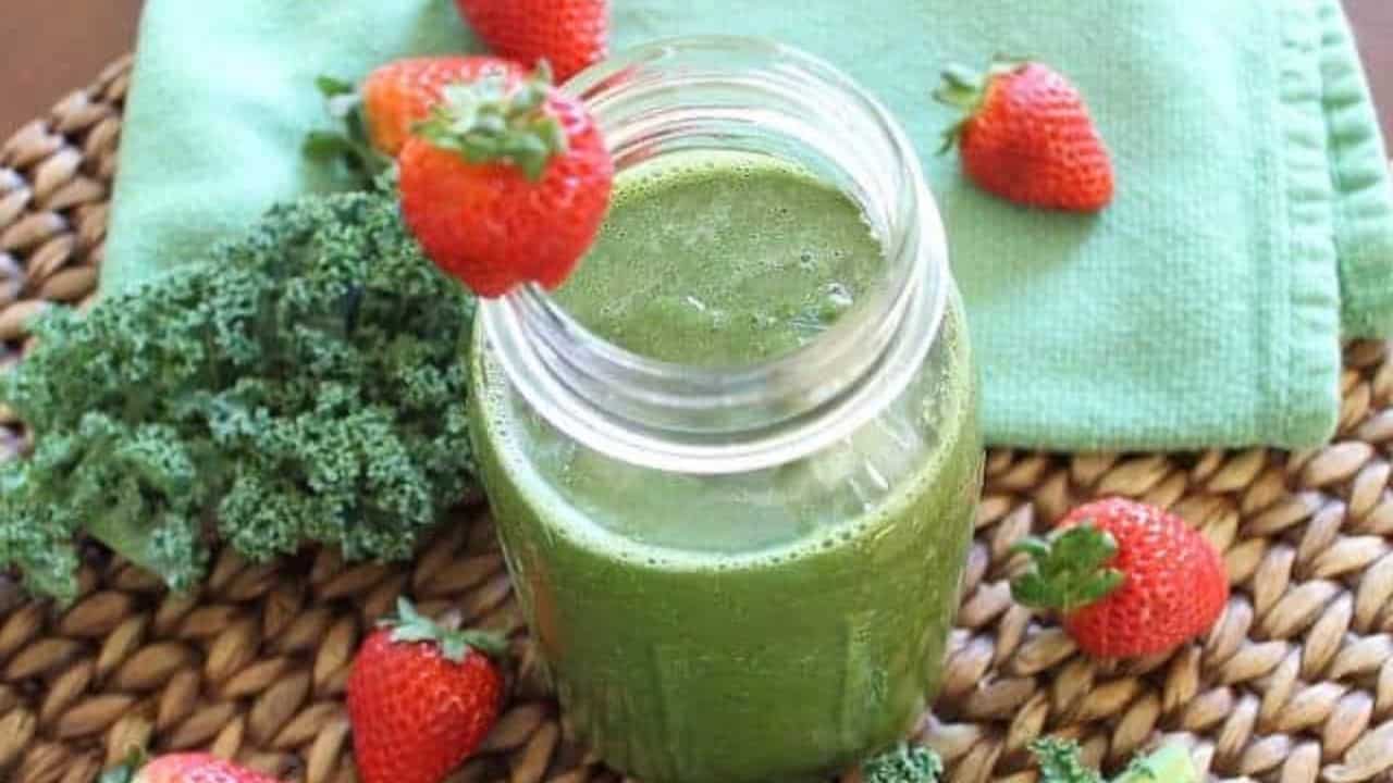 Strawberry orange kale smoothie with strawberry garnish in a mason jar.