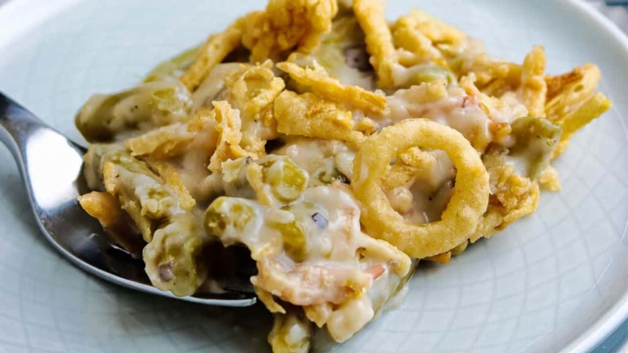 Slow cooker with green bean casserole topped with fried onions.