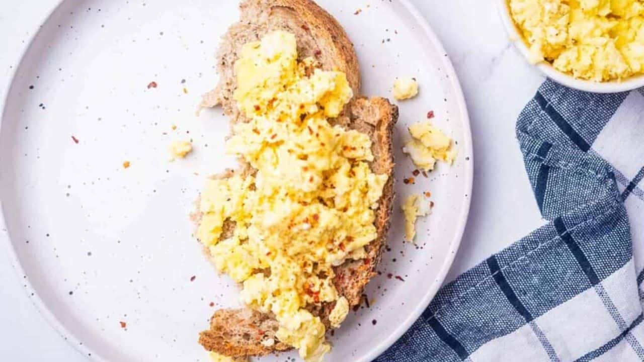 An overhead image of microwave scrambled eggs on a toast served on a plate.