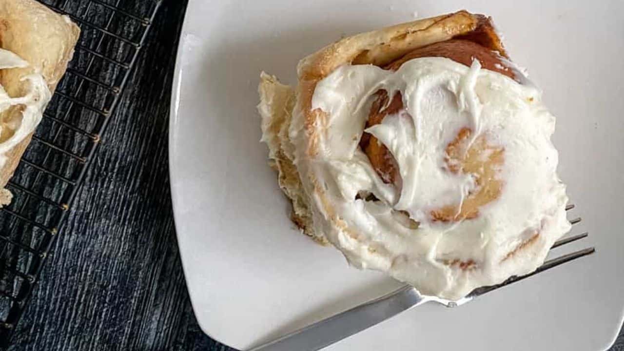 Gingerbread rolls with cream cheese frosting on a plate.