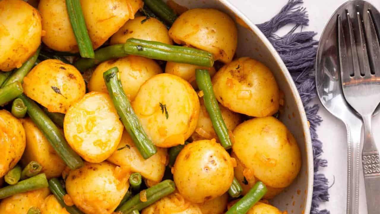 An image of green beans in a serving bowl with a spoon resting on it.