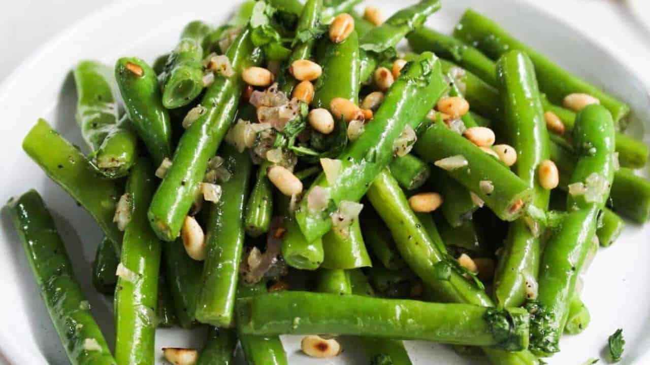 Green beans with pine nuts on a plate.