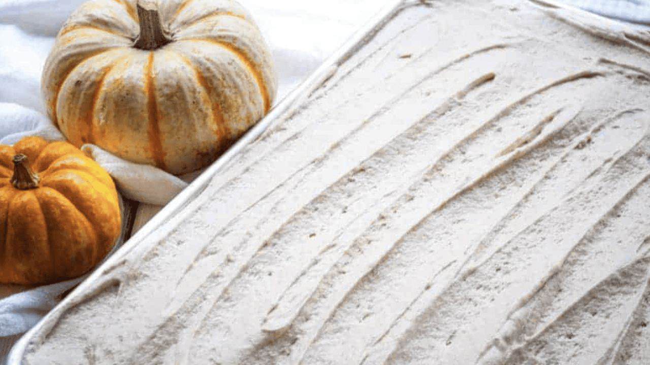 Pumpkin ice cream in a pan surrounded by pumpkins.