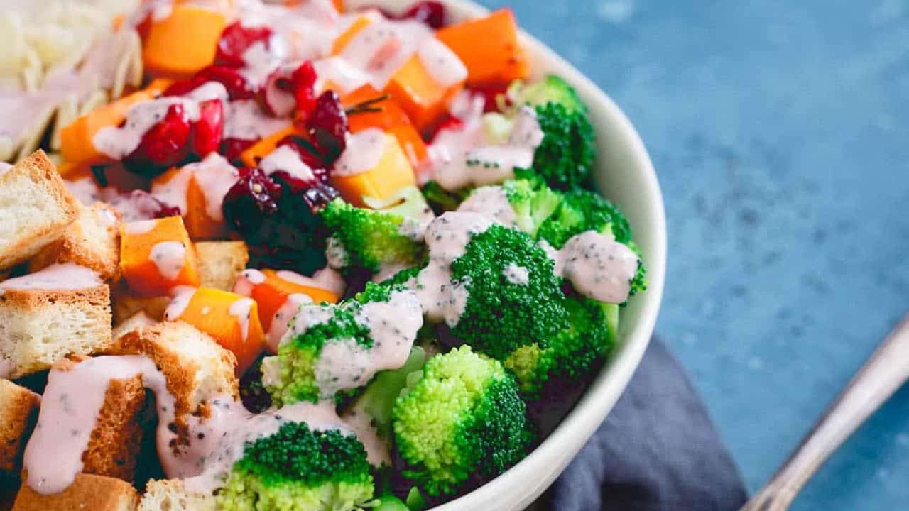 A bowl filled with broccoli, carrots and cranberries.