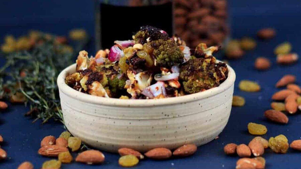 A bowl of roasted cauliflower with onions and sprigs of thyme.