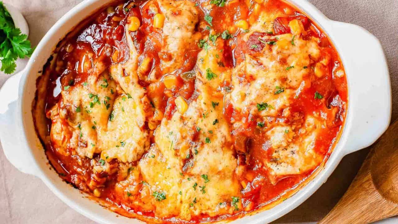 A white dish with chicken in a tomato sauce.