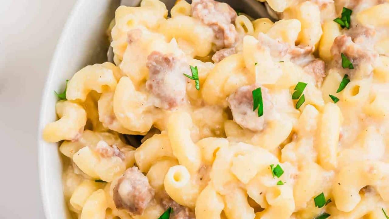 A bowl of macaroni and cheese with sausage and parsley.
