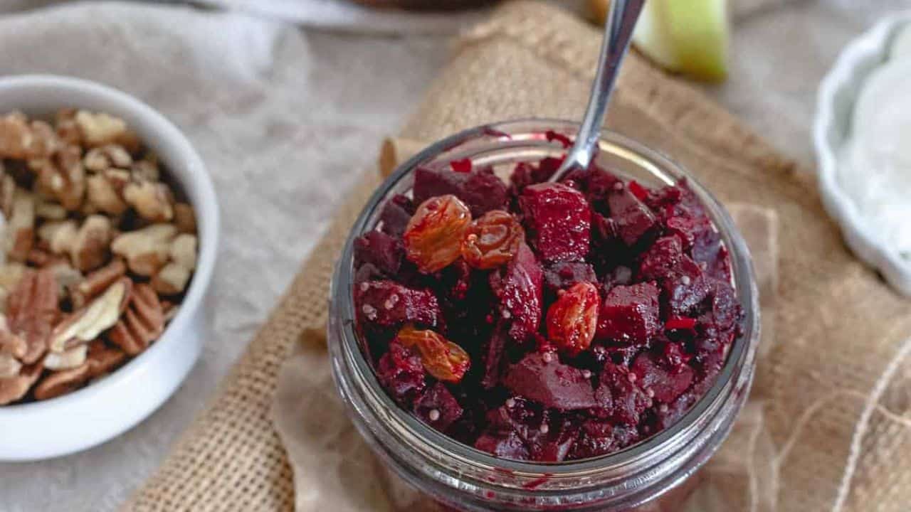 Spiced orange beet apple chutney in a small sauce pot with a spoon.