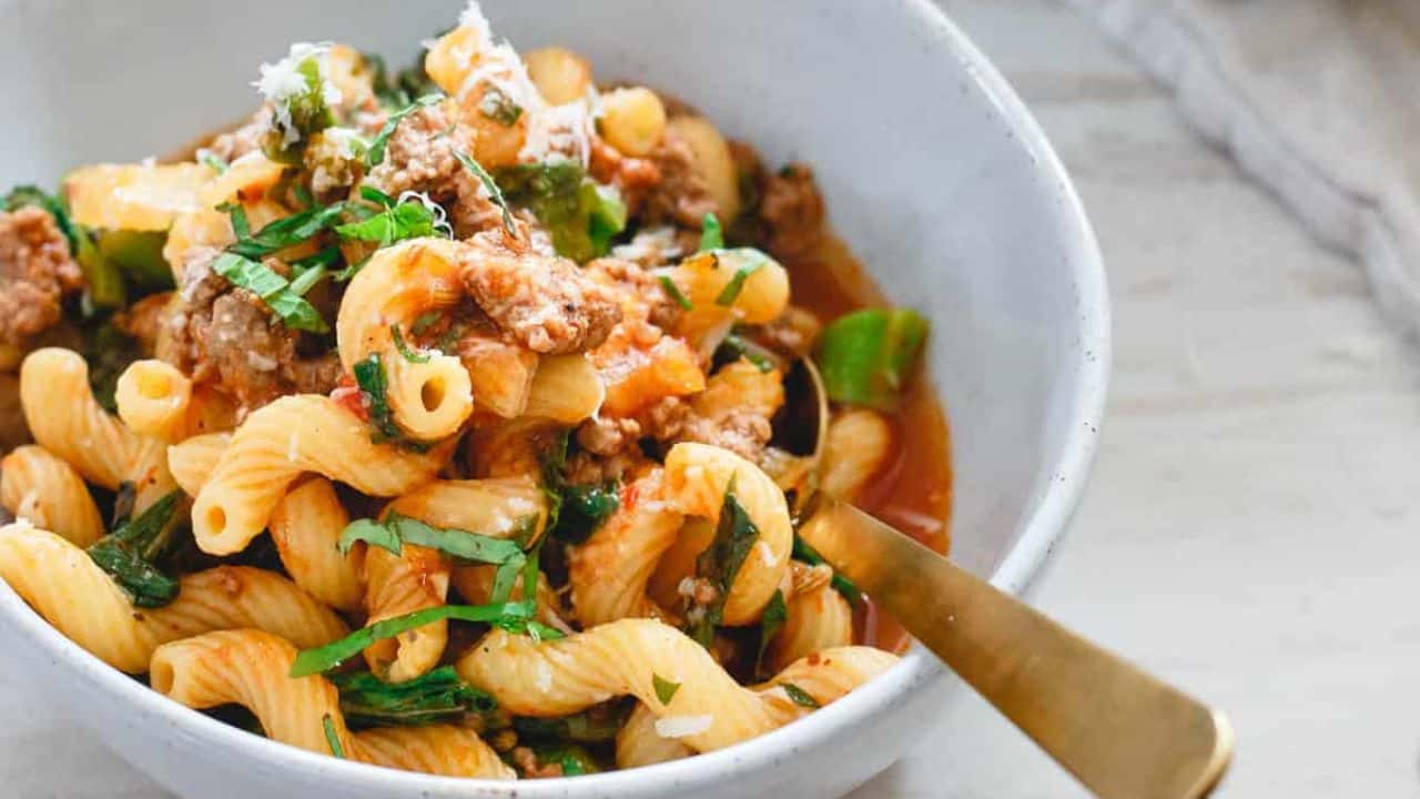 Lamb ragu with cavatappi pasta in a white skillet.