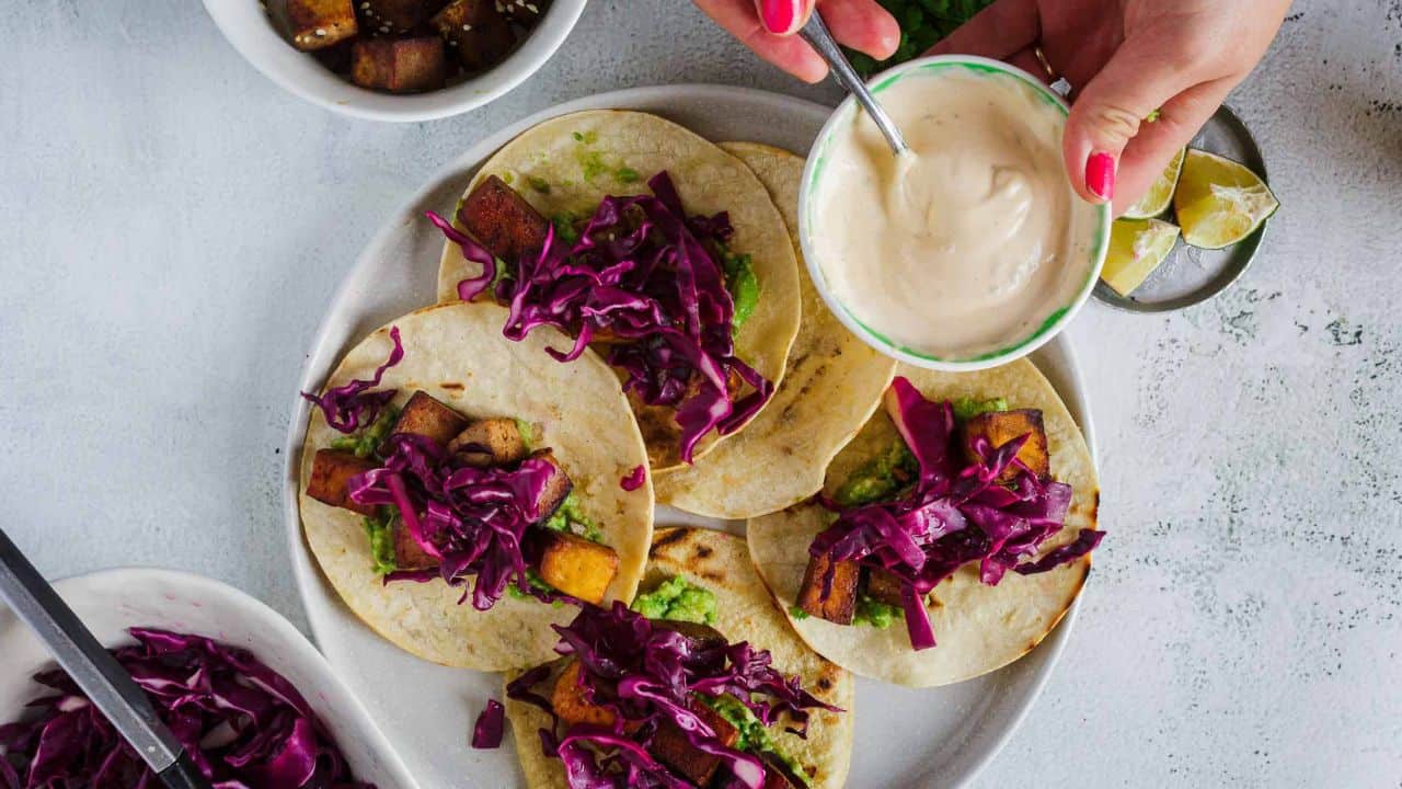 Side view of tacos on a plate, one with bite taken out.