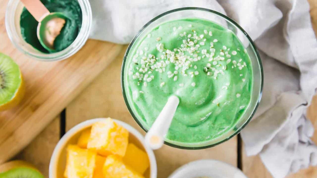Spirulina smoothie in a glass with hemp seeds and straw.