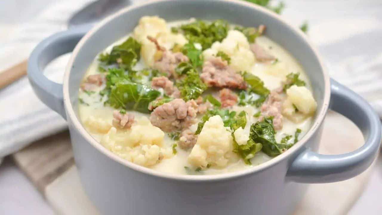 A bowl of soup with meat and kale.