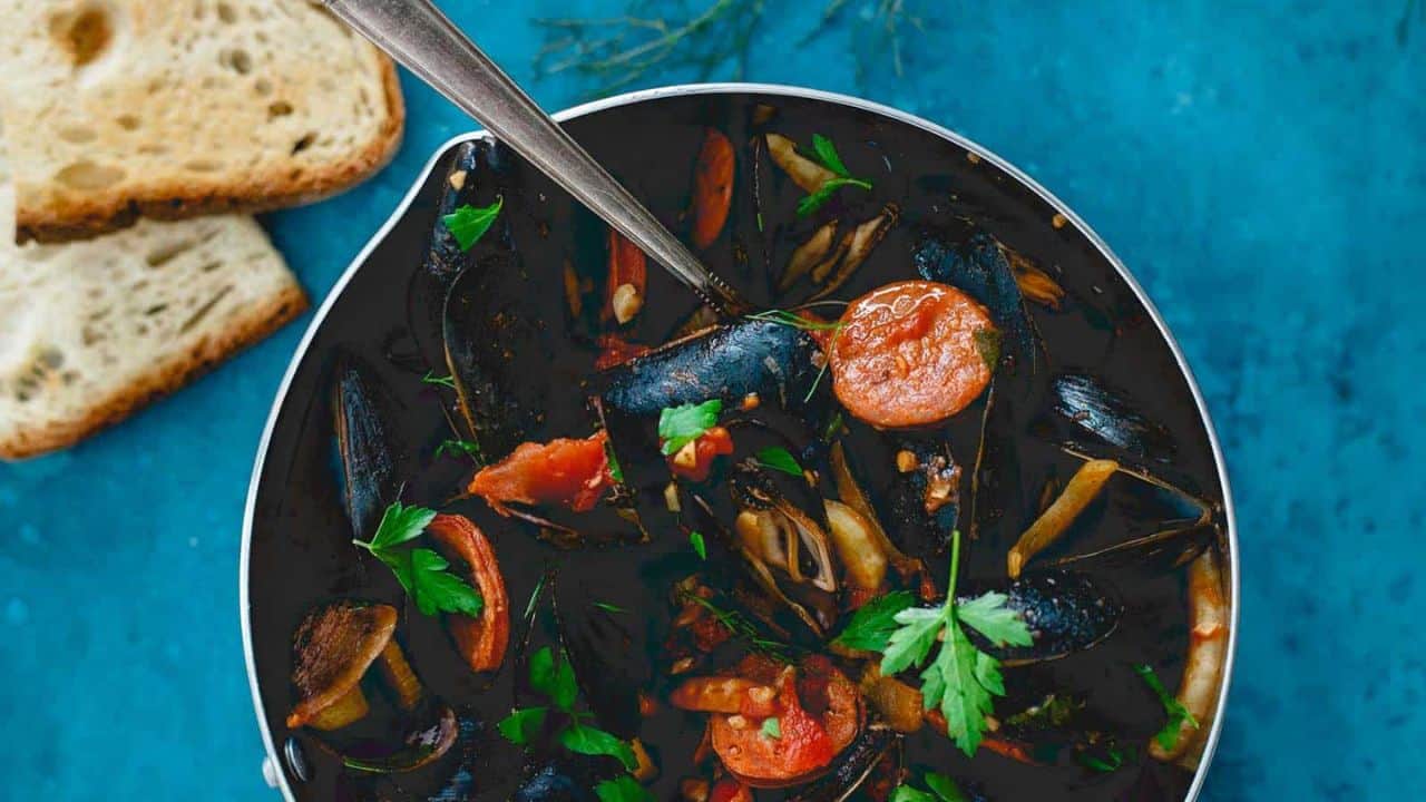 Mussels with chorizo and chilis in a pot.