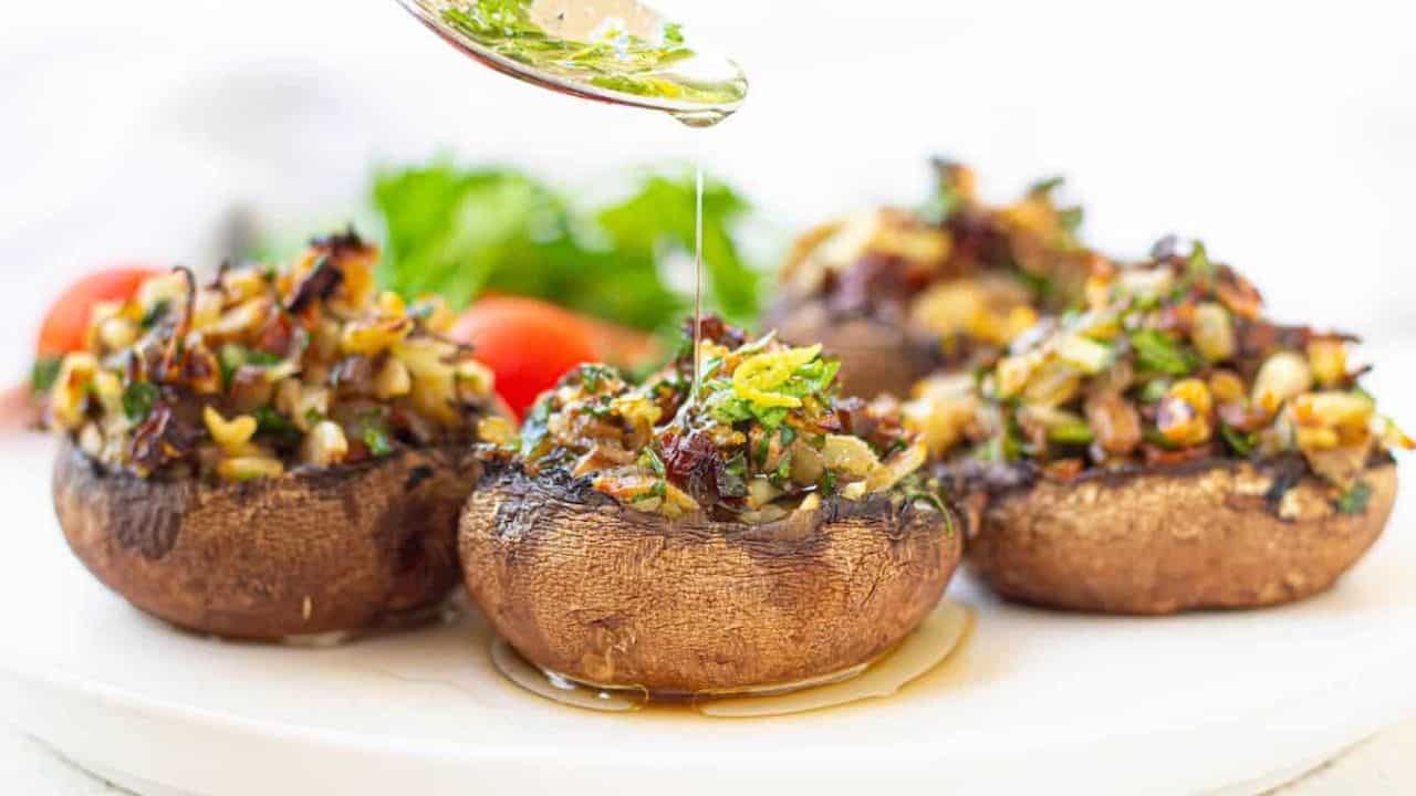 A white plate with vegan stuffed portobello mushrooms garnished with cherry tomatoes and parsley.
