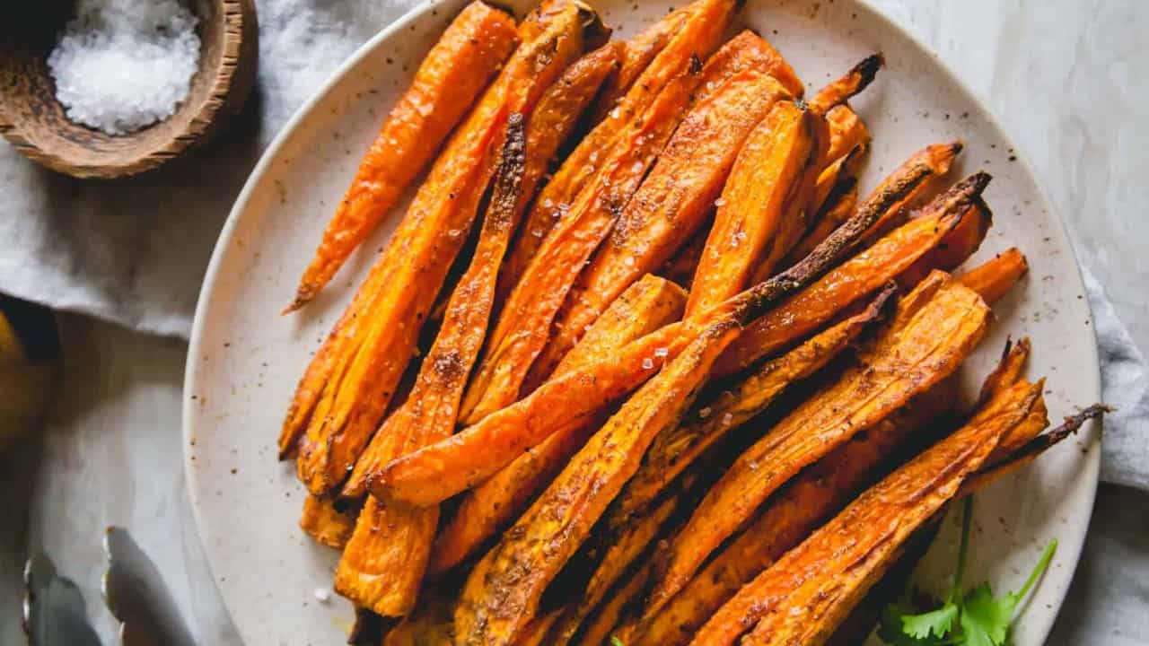 Simply seasoned roasted air fryer carrots on a plate with coarse sea salt garnish.