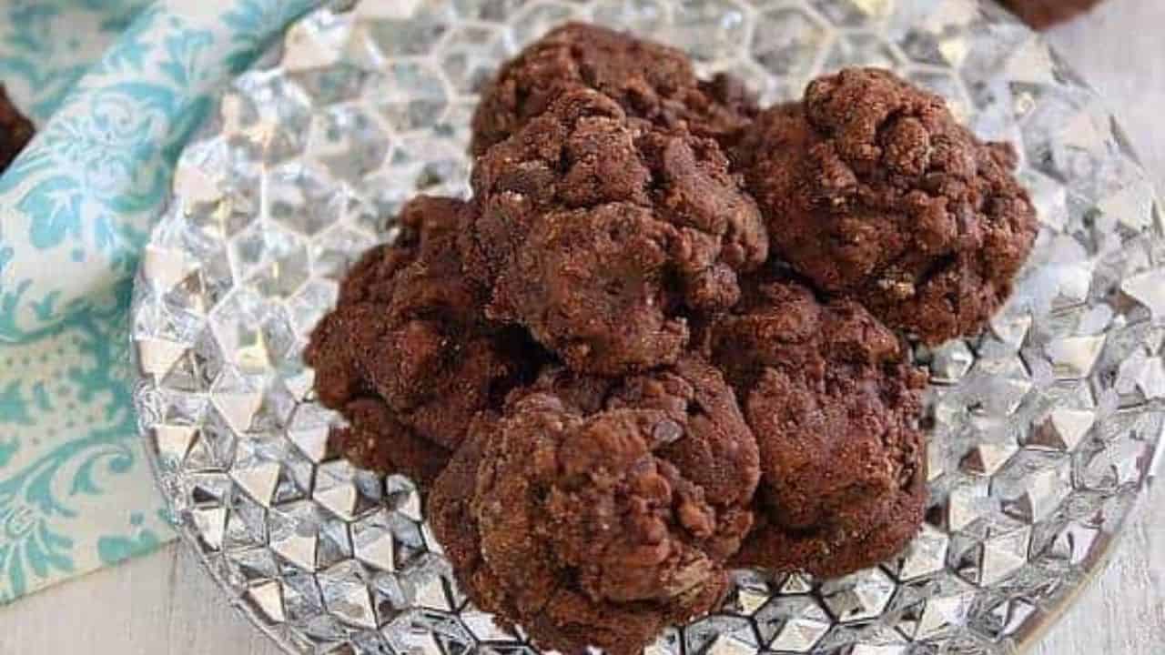 Chocolate oatmeal cookies on a silver plate with a glass of milk.