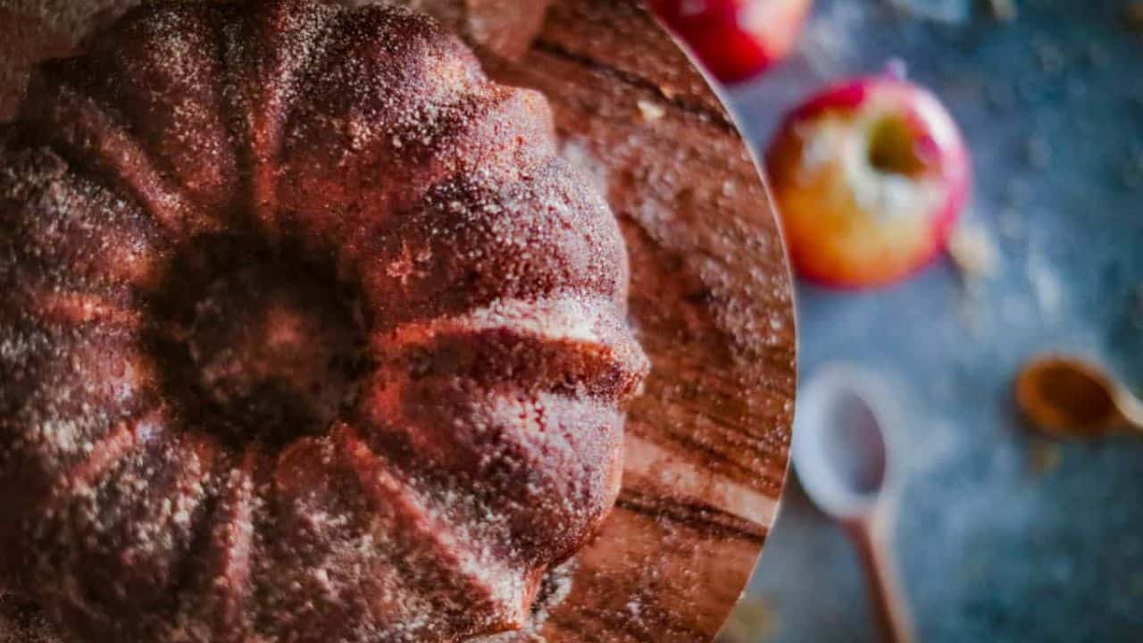 Overhead shot of this apple bundt cake on a cake stand with apples in the background.
