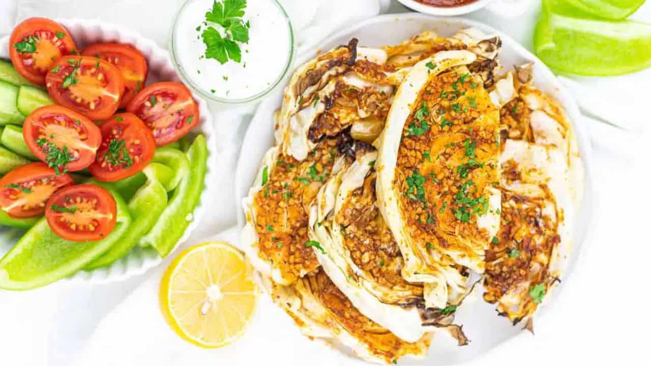 A plate of grilled cabbage wedges topped with herbs.