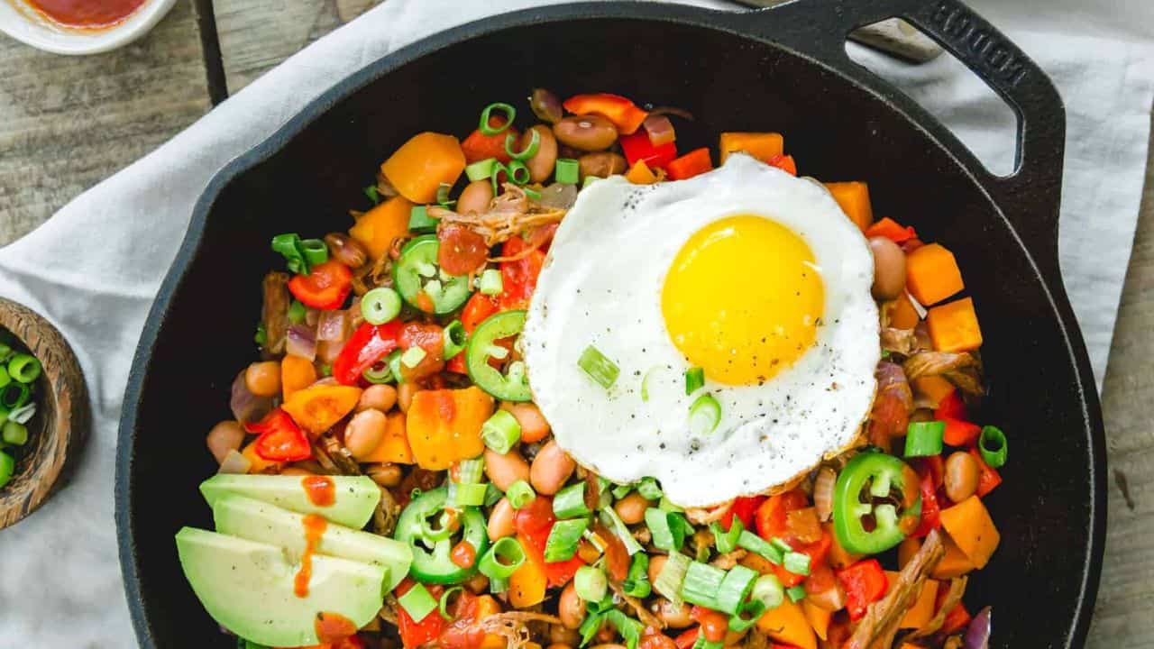 Brisket hash with a fried egg in a cast iron skillet.