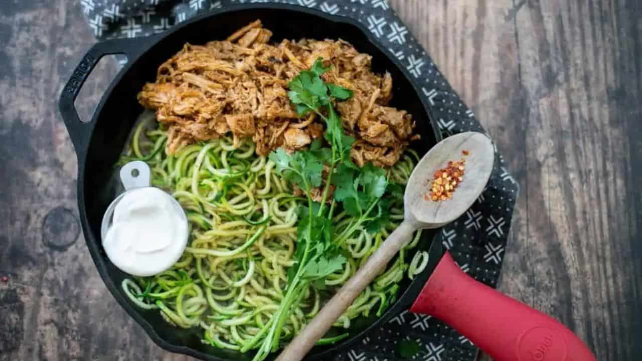 A skillet with carnitas and zucchini noodles in it.