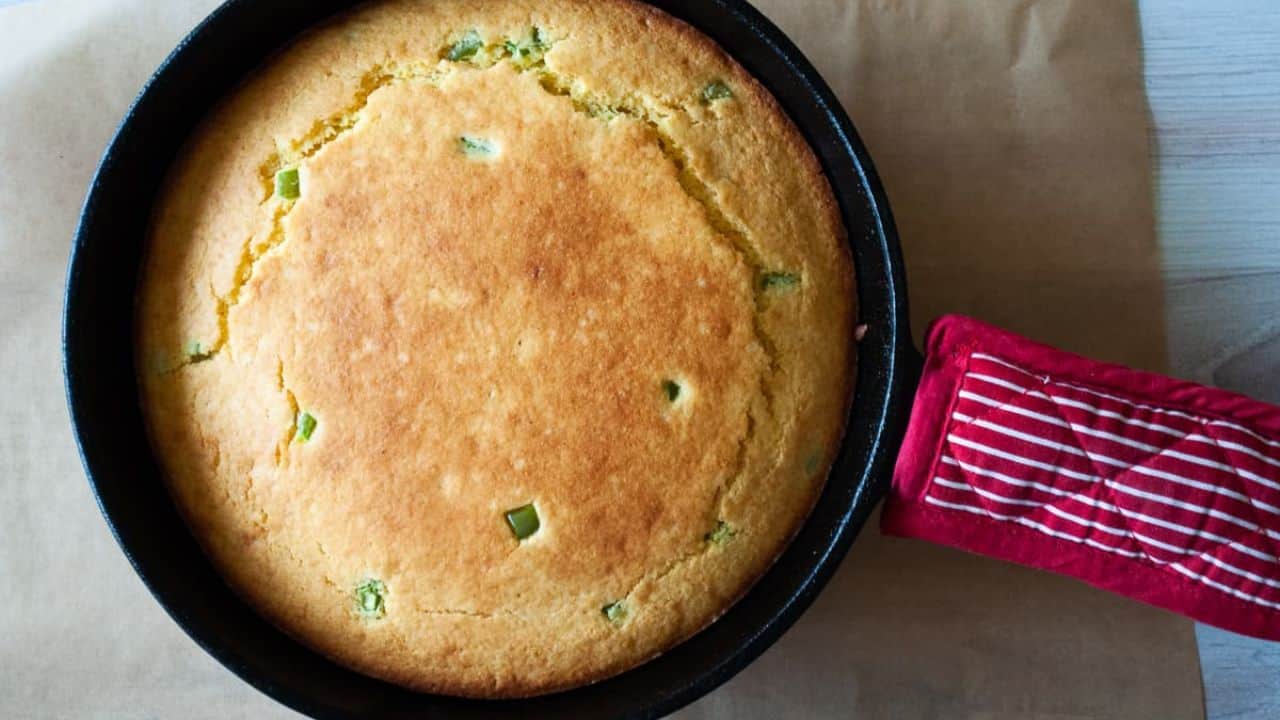 A cast irons skillet with jalapeño corn bread in it.