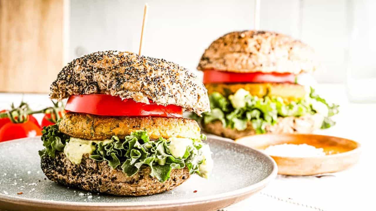 Low angle shot of 2 chickpea burgers on seeded buns with all the fixings.
