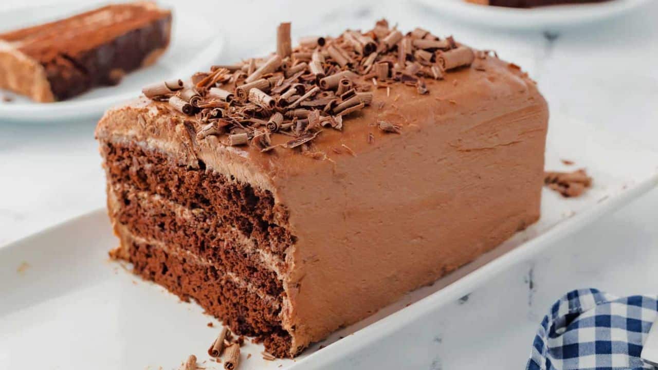 A three layer chocolate cake on a white platter.