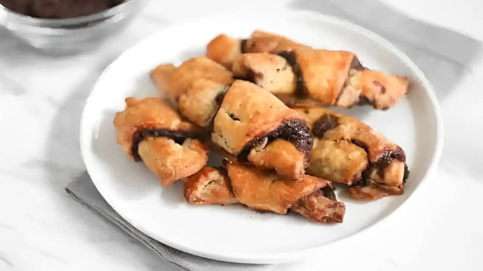 Chocolate croissants on a plate with a cup of coffee.