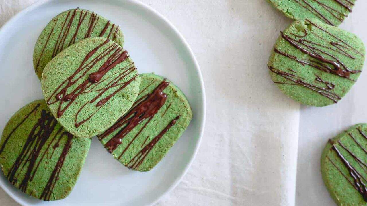 Green cookies with chocolate drizzle on a baking sheet.