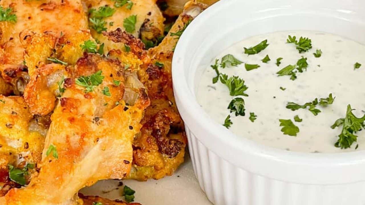 Crispy air fried lemon pepper wings served with a dipping sauce on a plate.