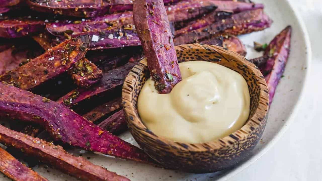Purple sweet potato fries on a plate with dipping sauce.