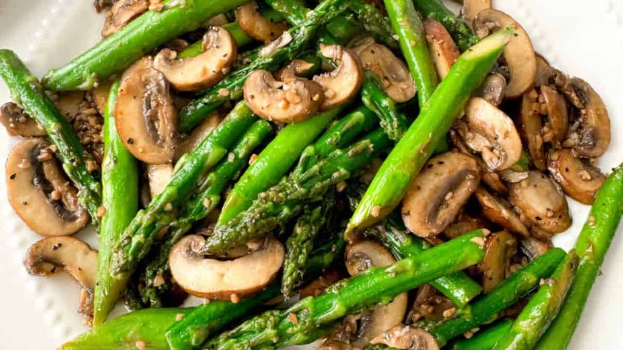 Sauteed asparagus and mushrooms on a white plate.