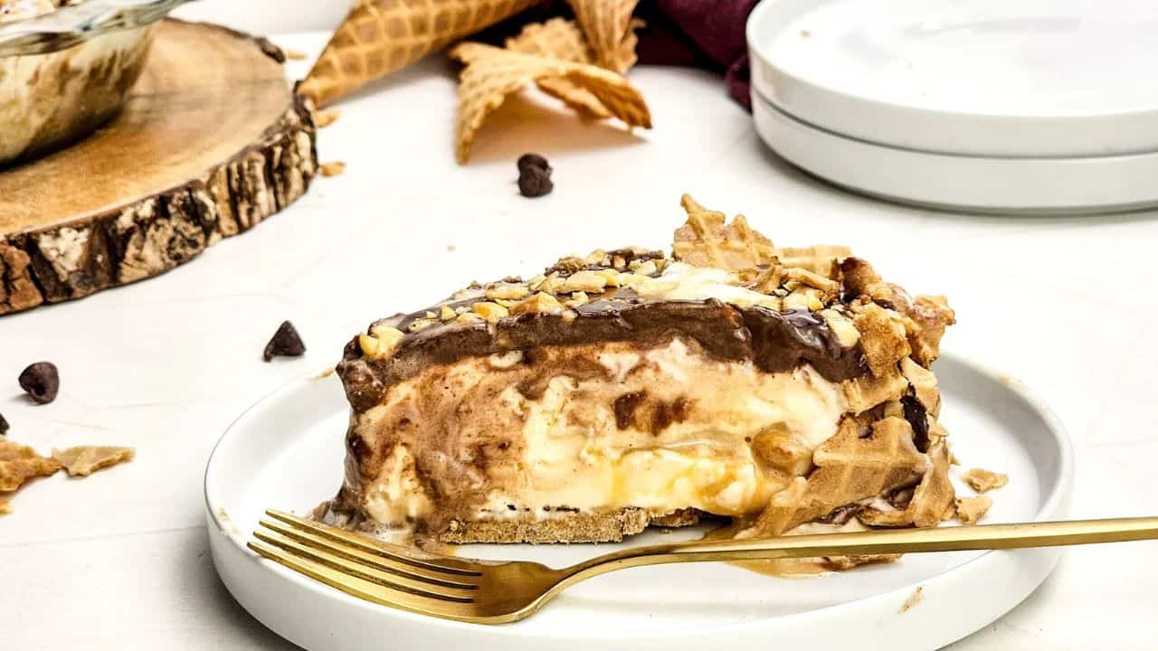 Piece of pie on a white plate with gold fork.