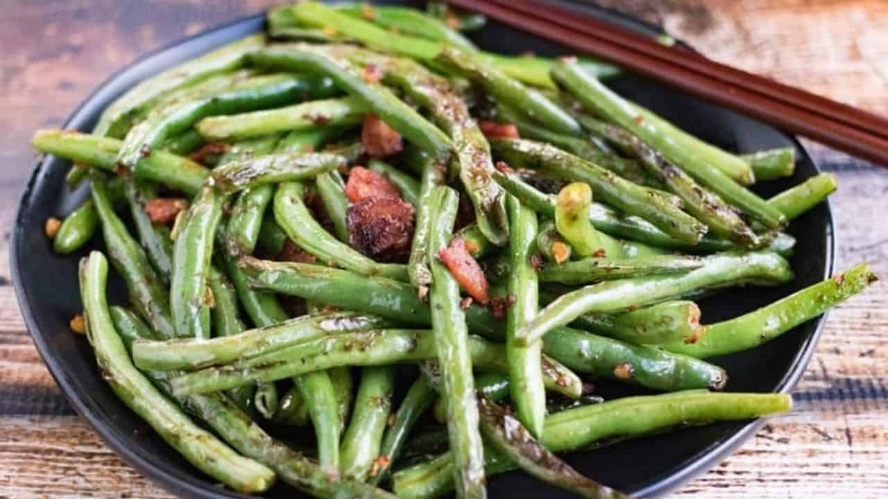 Low angle shot of a plate of dry fried green beans.