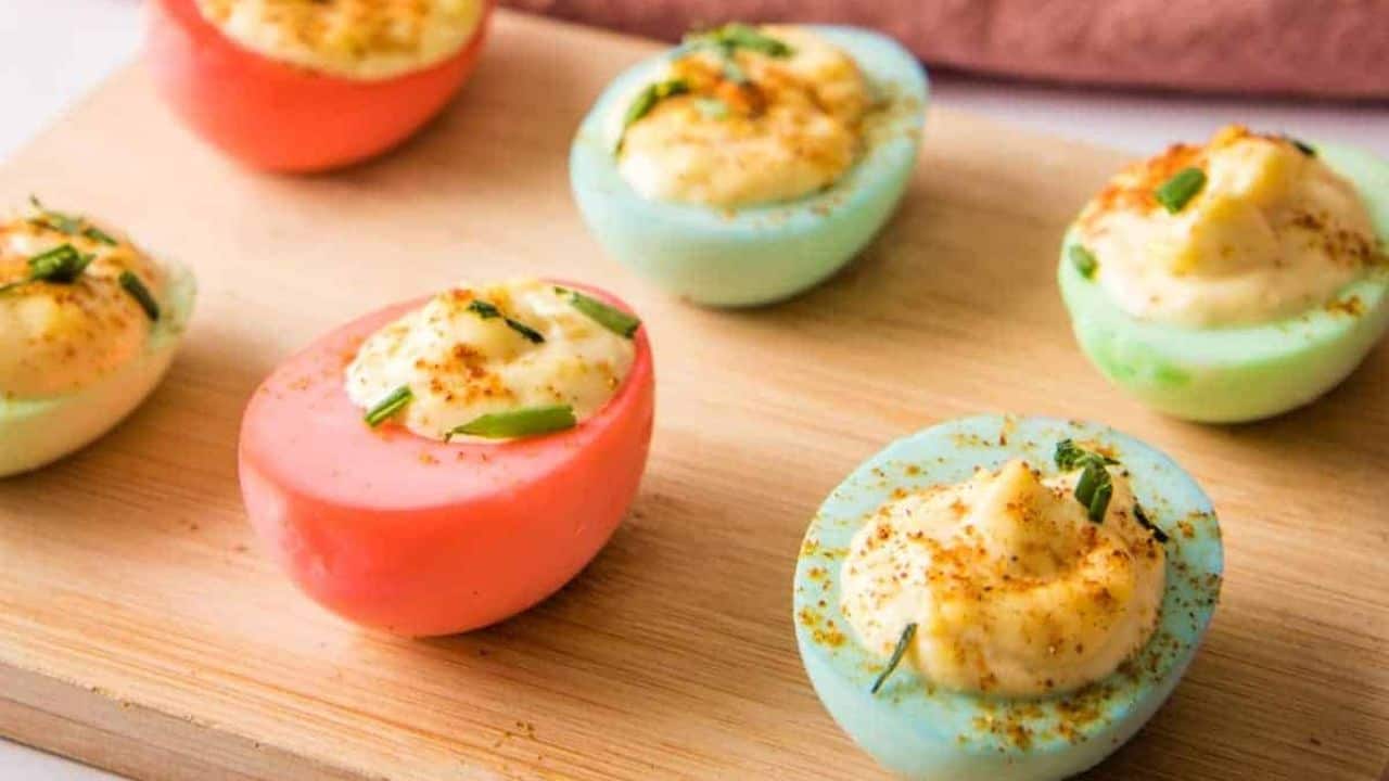 Side view of Easter deviled eggs on a wooden platter with a pink towel in the background.