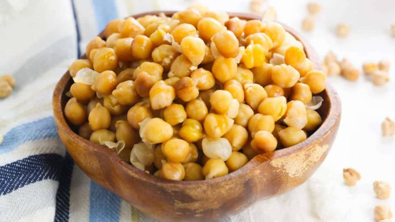 Close-up of cooked Instant Pot chickpeas in a brown wooden bowl.