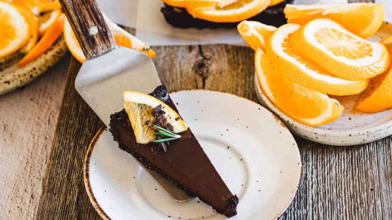 A chocolate tart with orange slices and rosemary.