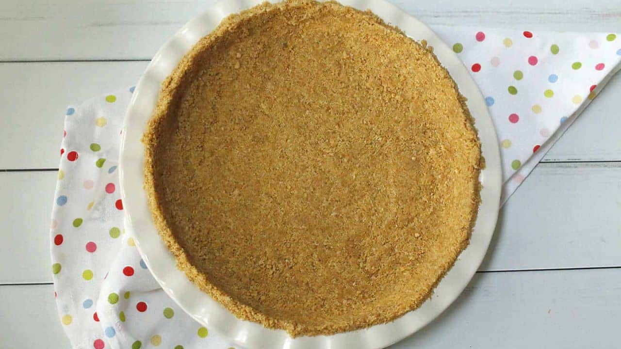 A graham pie crust on a white plate with polka dots.