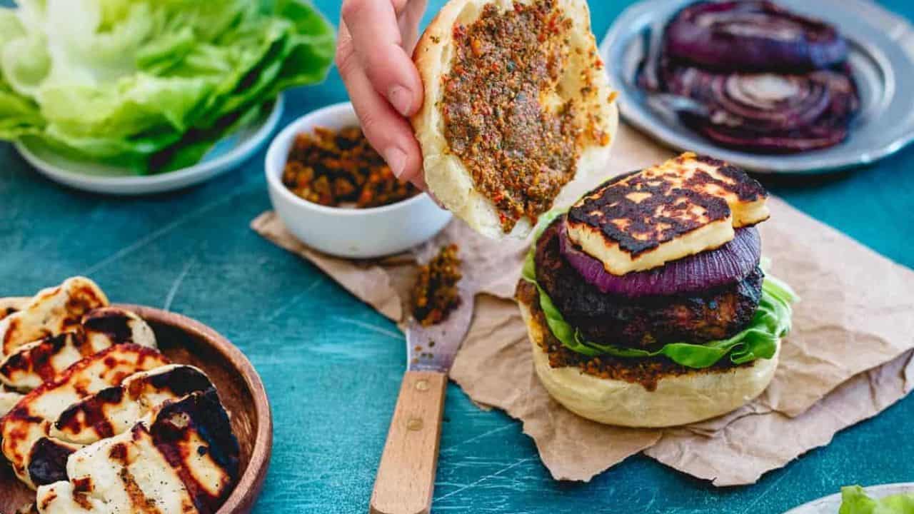 Grilled halloumi lamb burger on a bun with pesto spread.
