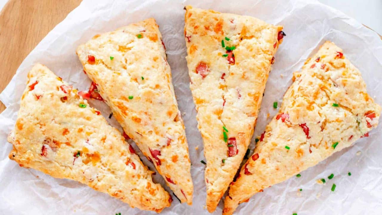 Four ham and cheese scones on a piece of white paper.