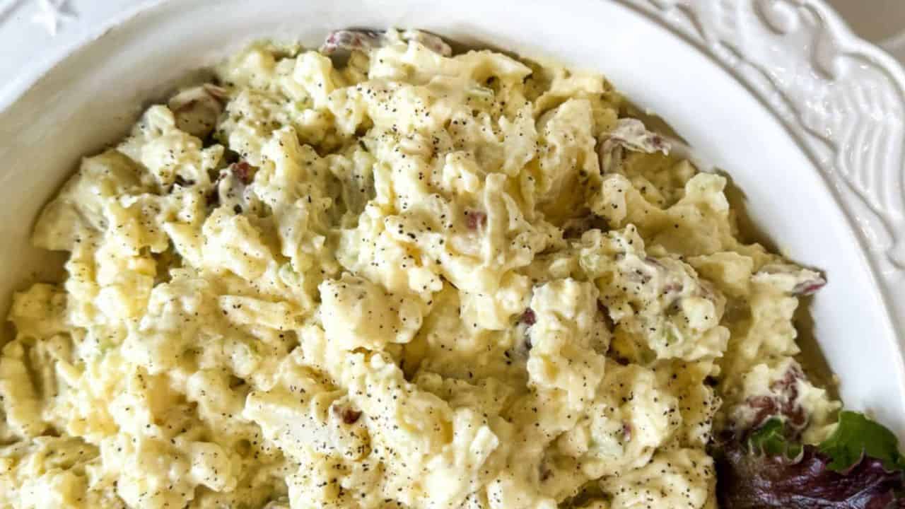 Hearty Penna Dutch Potato Salad in a patriotic motif serving bowl with a spoon.