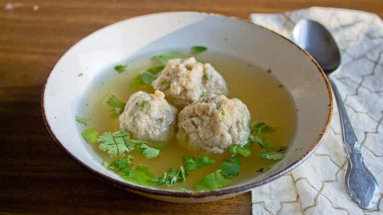 Close up on 3 matzo balls in soup.