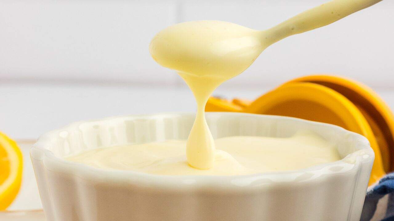 A bowl of mayonnaise with a spoonful.