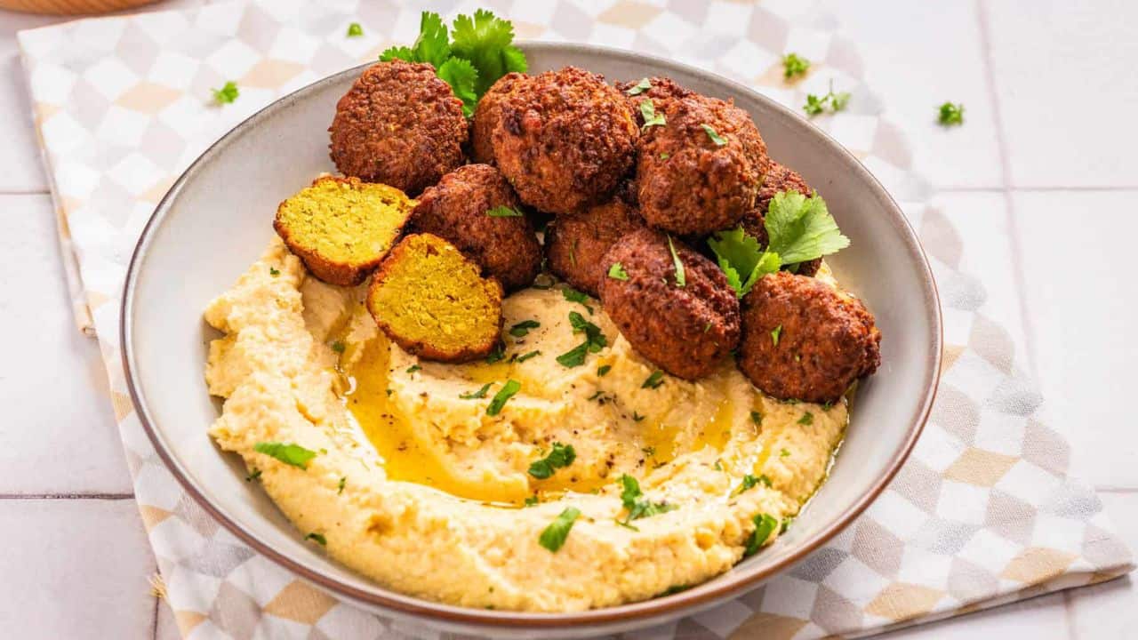 A close up image of falafels on a bowl of hummus.